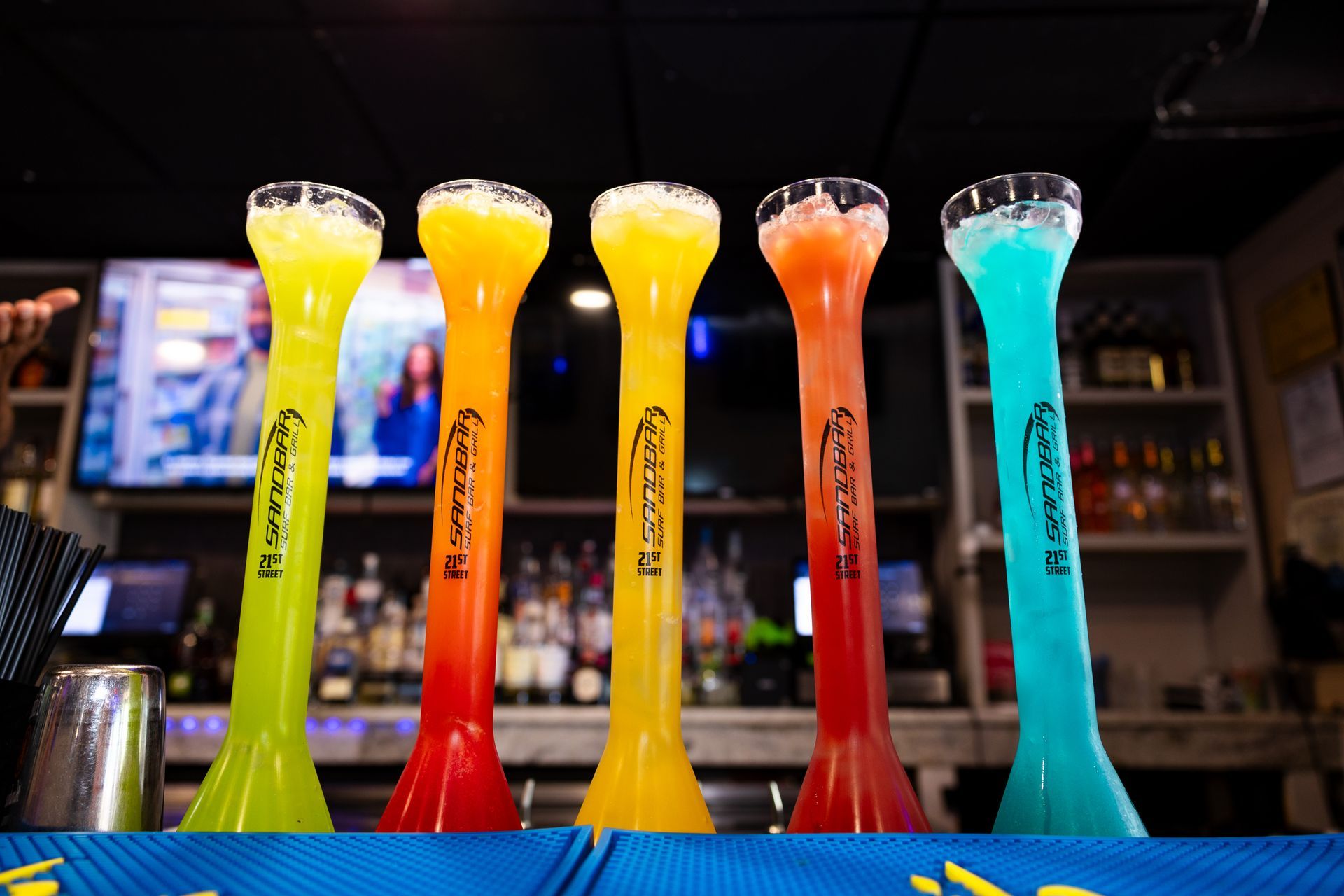 A row of shot glasses filled with different colored drinks on a bar.