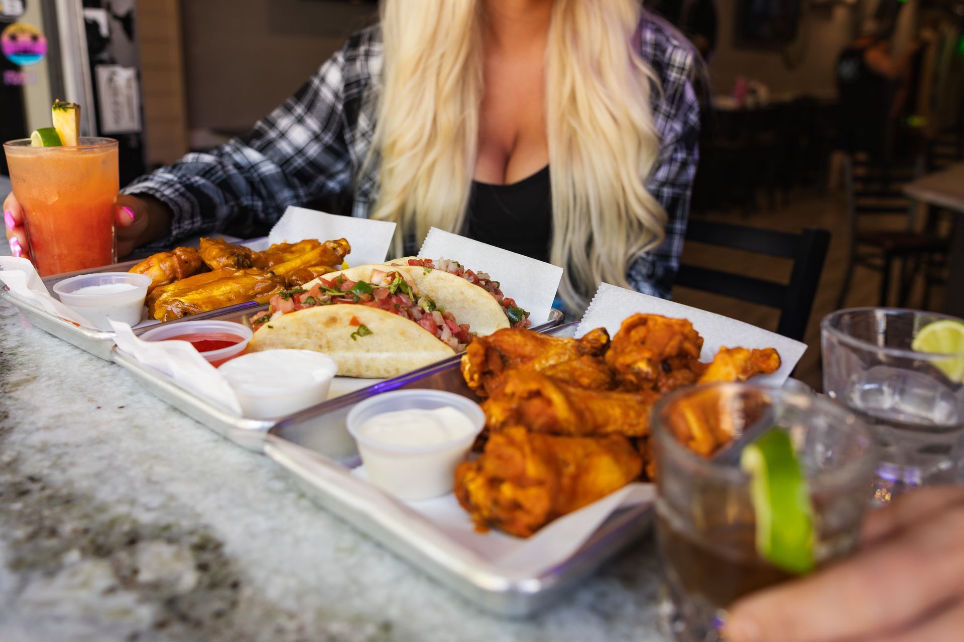A woman is sitting at a table with a tray of food and drinks.