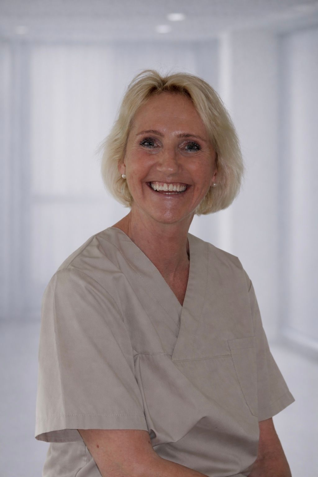 Eine Frau im lila OP-Kittel lächelt in die Kamera.