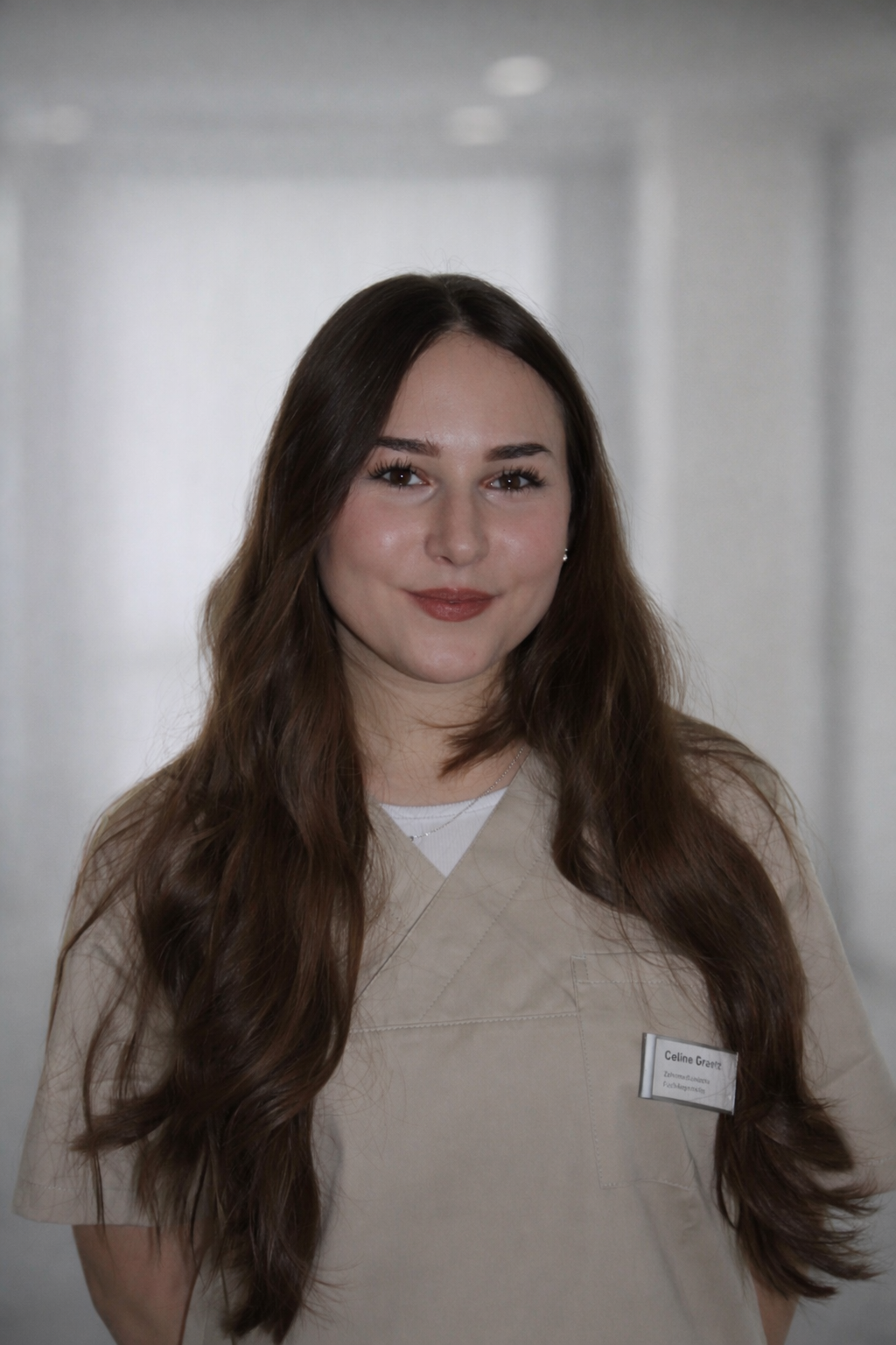 Eine Frau im lila OP-Kittel lächelt in die Kamera.