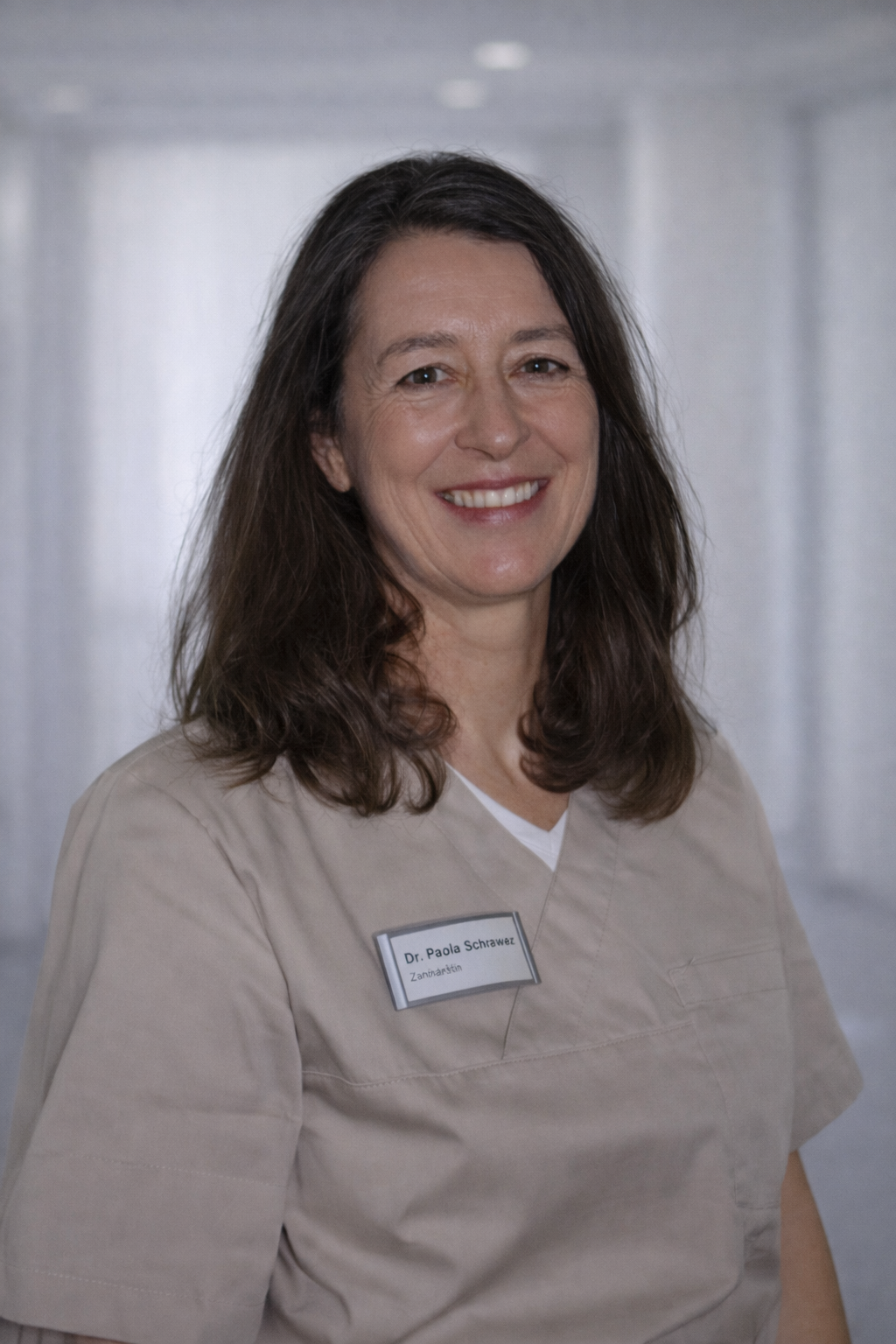 Eine Frau im lila OP-Kittel lächelt in die Kamera.