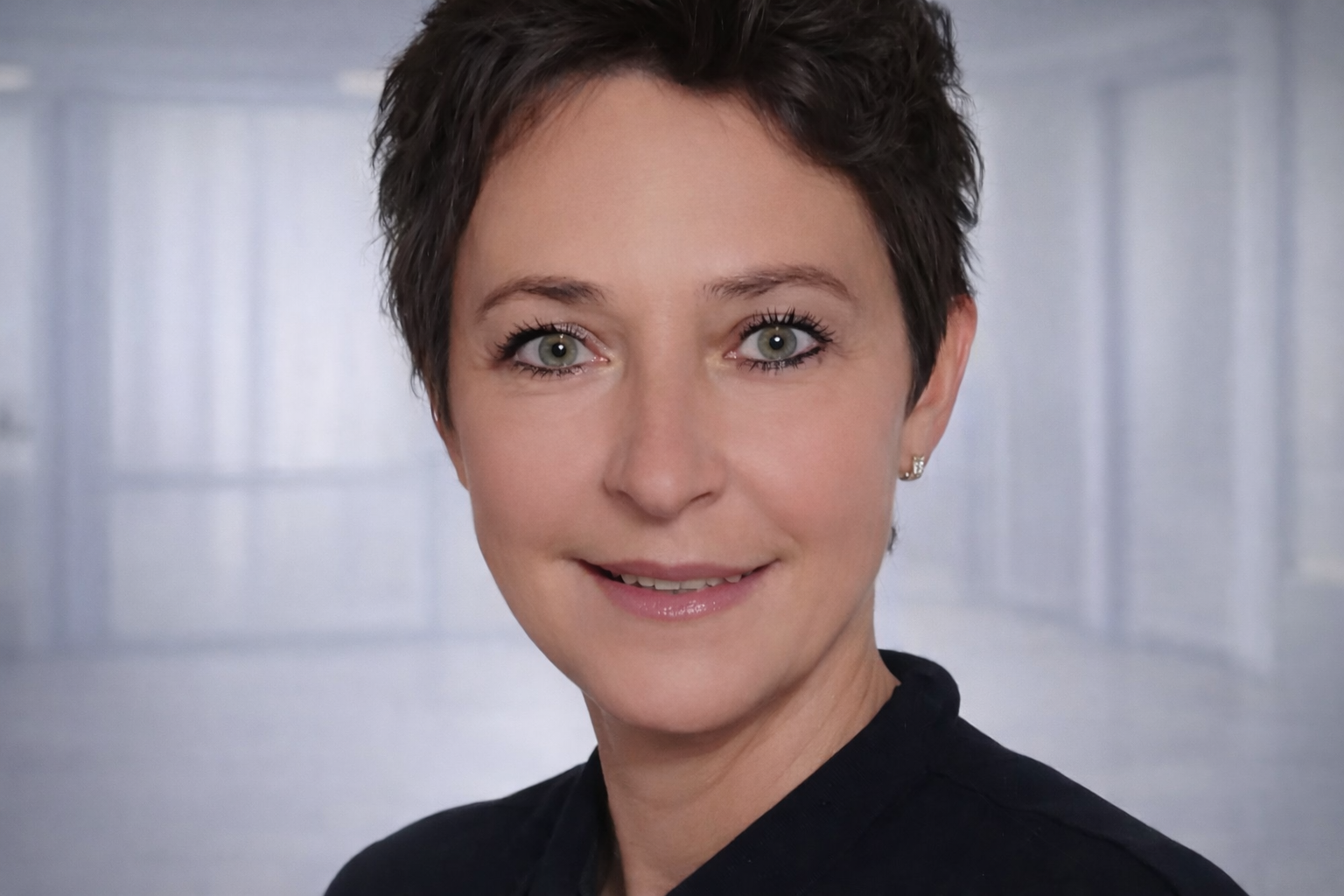 Eine Frau im lila OP-Kittel lächelt in die Kamera.