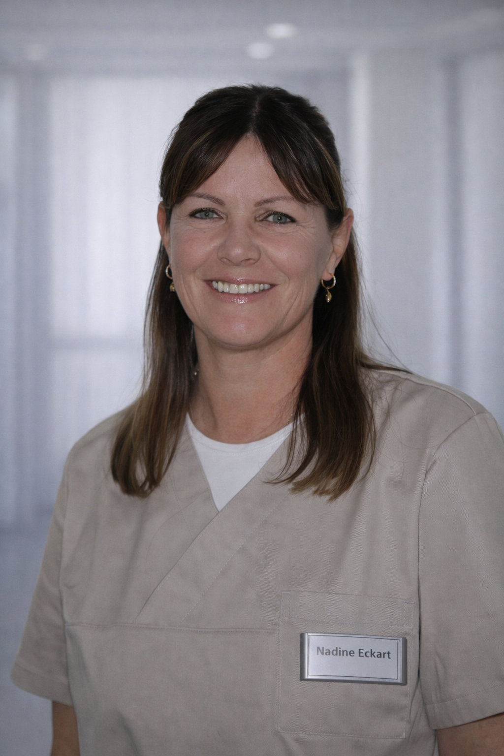 Eine Frau im lila OP-Kittel lächelt in die Kamera.