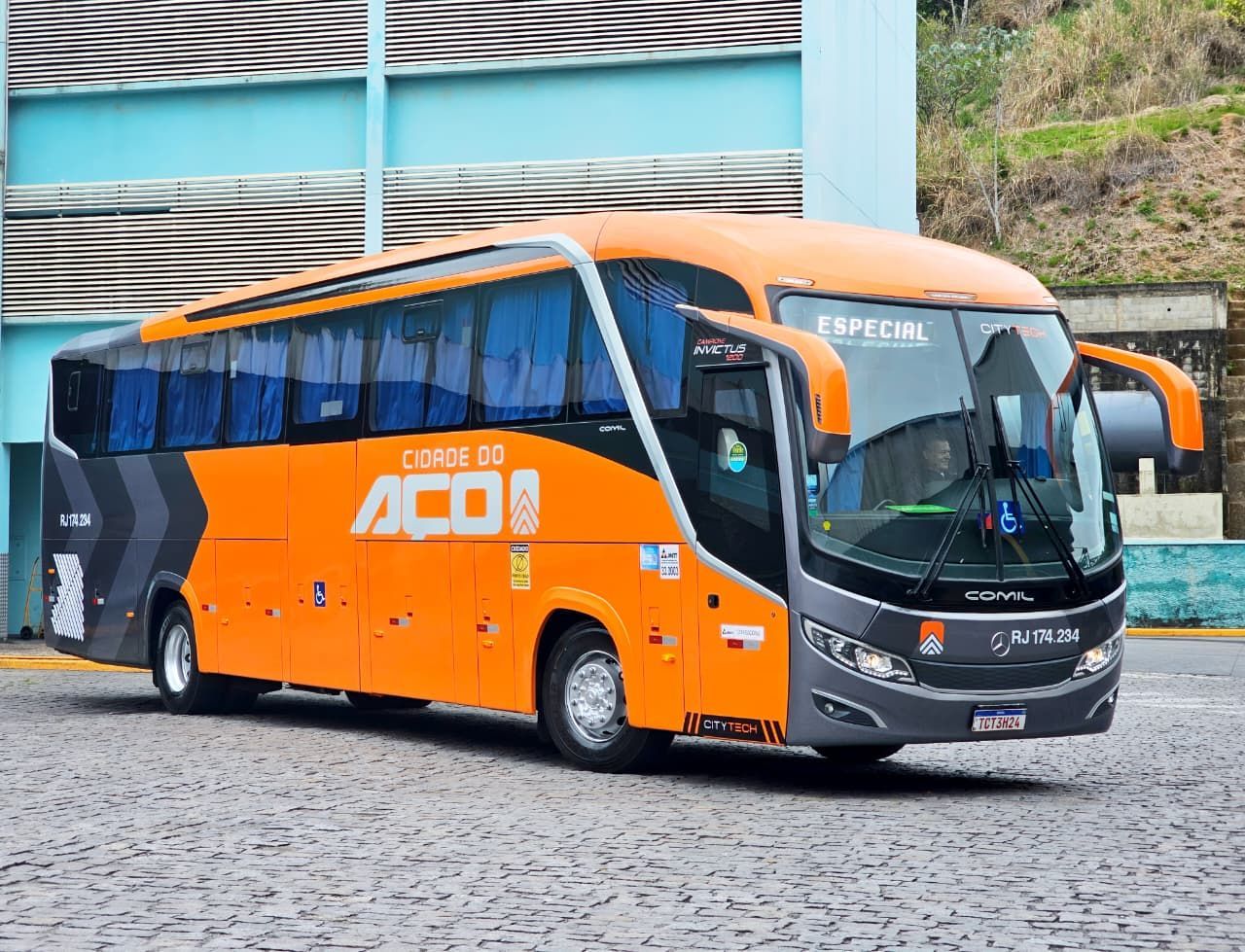 Uma van Mercedes Sprinter branca com detalhes em laranja e cinza estacionada. Logotipo 
