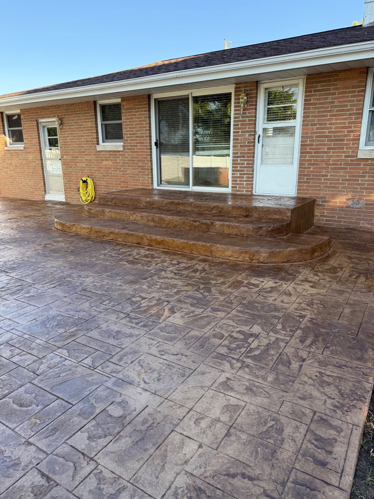 Brick house exterior with stamped concrete patio and steps.