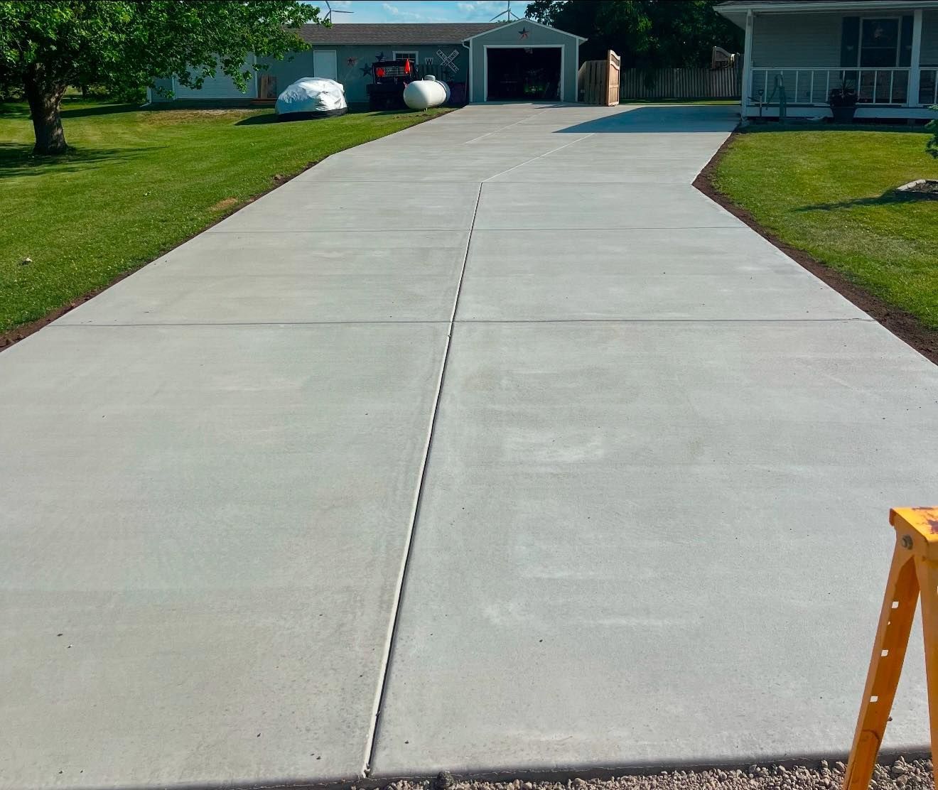 Newly poured concrete driveway leading to a garage and house on a sunny day.
