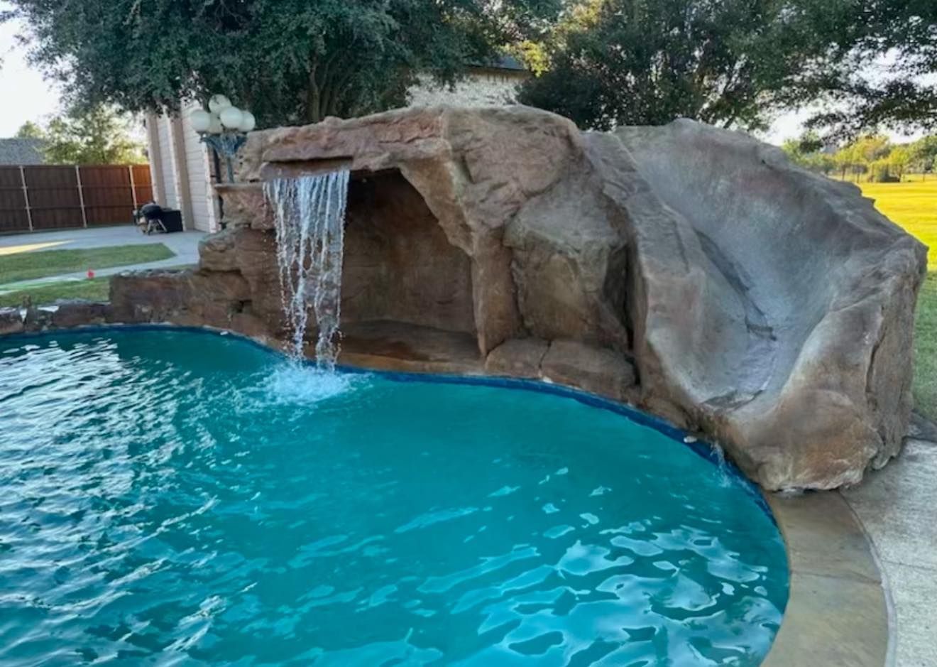 Pool with turquoise water, rock edging, and concrete deck.