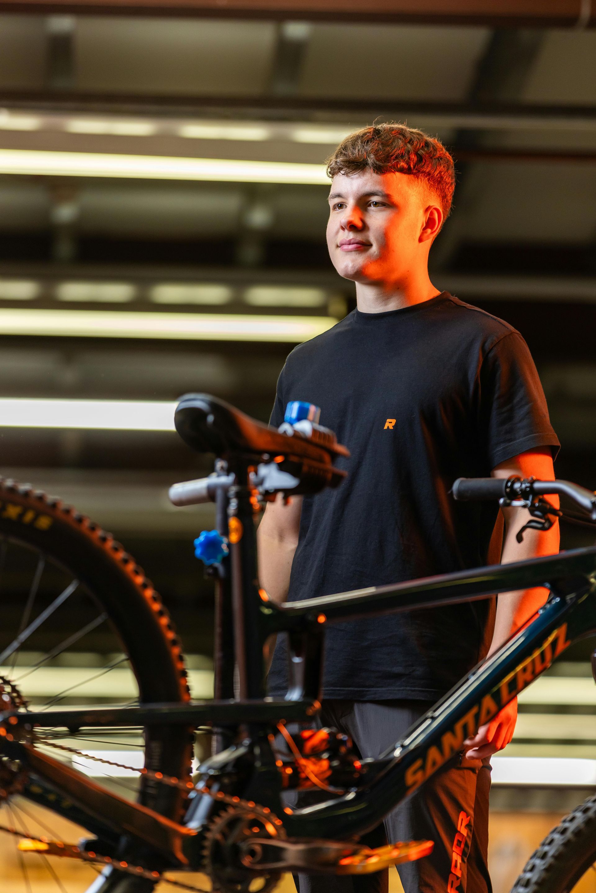 A young man is standing next to a bicycle in a garage.