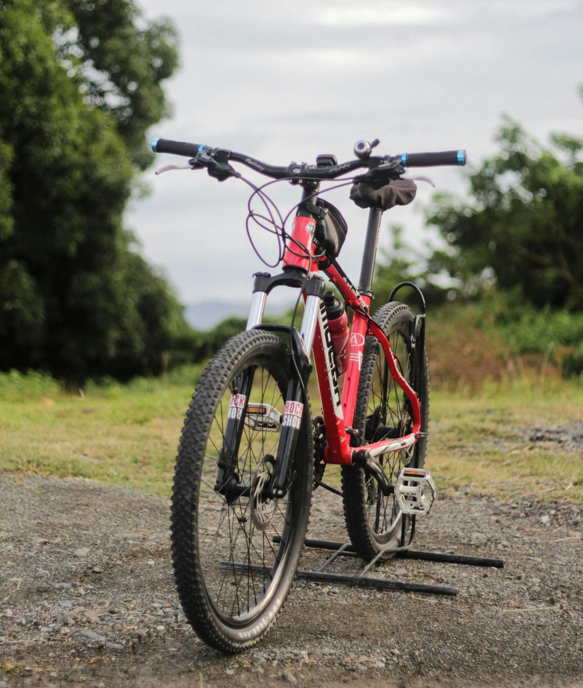 A red bicycle is parked on a dirt road.