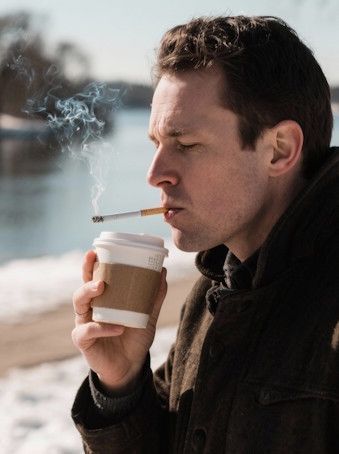 Minneapolis man smoking a cigarette and drinking a coffee in an ice cold Minnesota winter