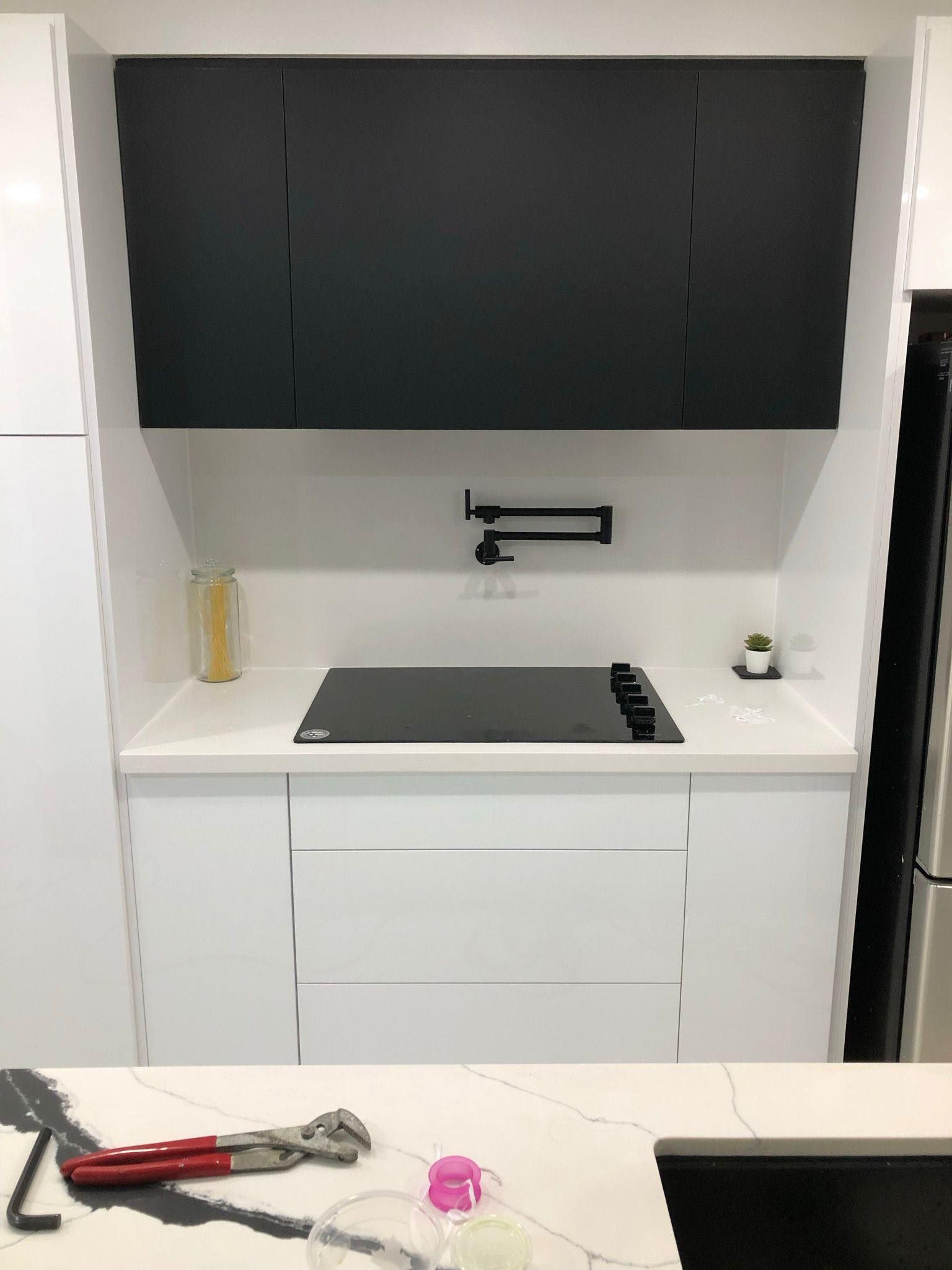 A kitchen with white cabinets and a black stove top oven.