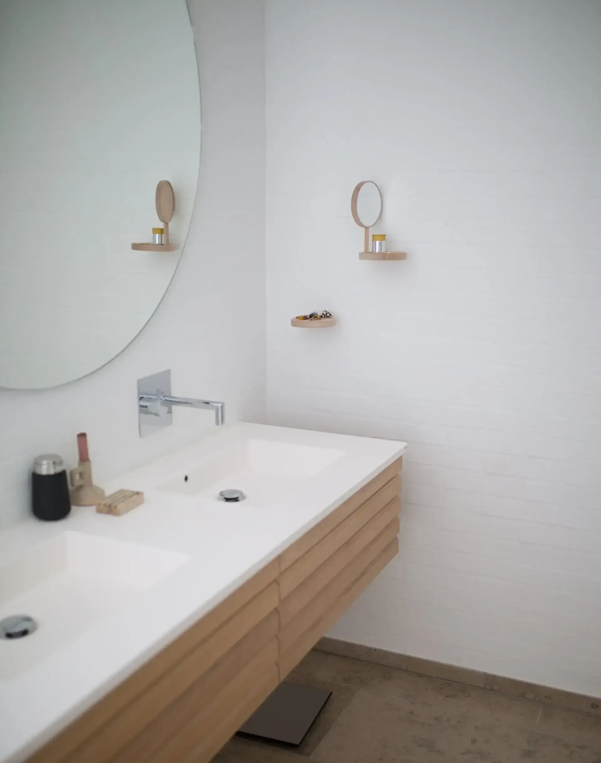 A bathroom with two sinks and a round mirror