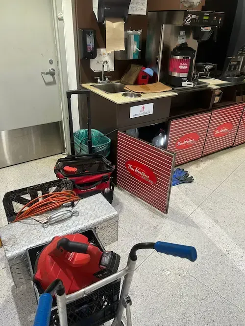 Powerflushing drain cleaning service at a Tim Hortons commercial kitchen in Oakville, featuring professional-grade equipment used to clear grease and food buildup from under-sink drains