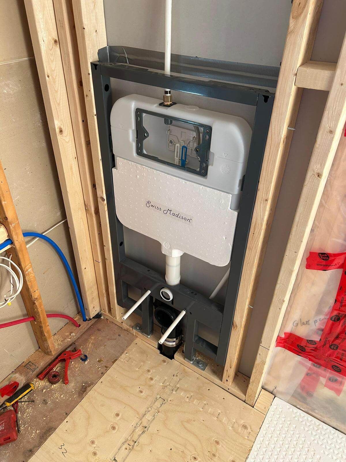 A wall mounted toilet is being installed in a bathroom.