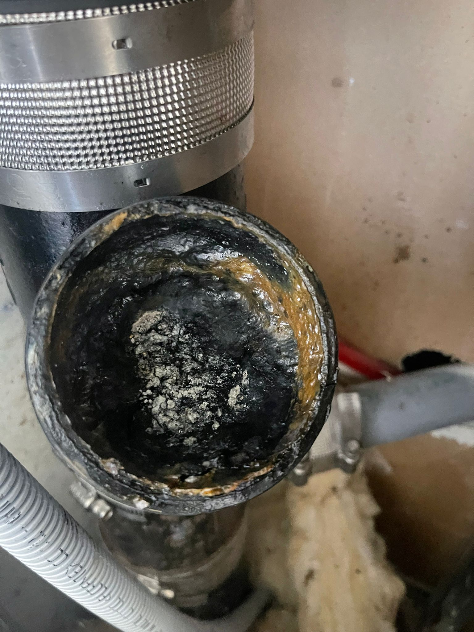 A close up of a dirty pipe with a hose attached to it.