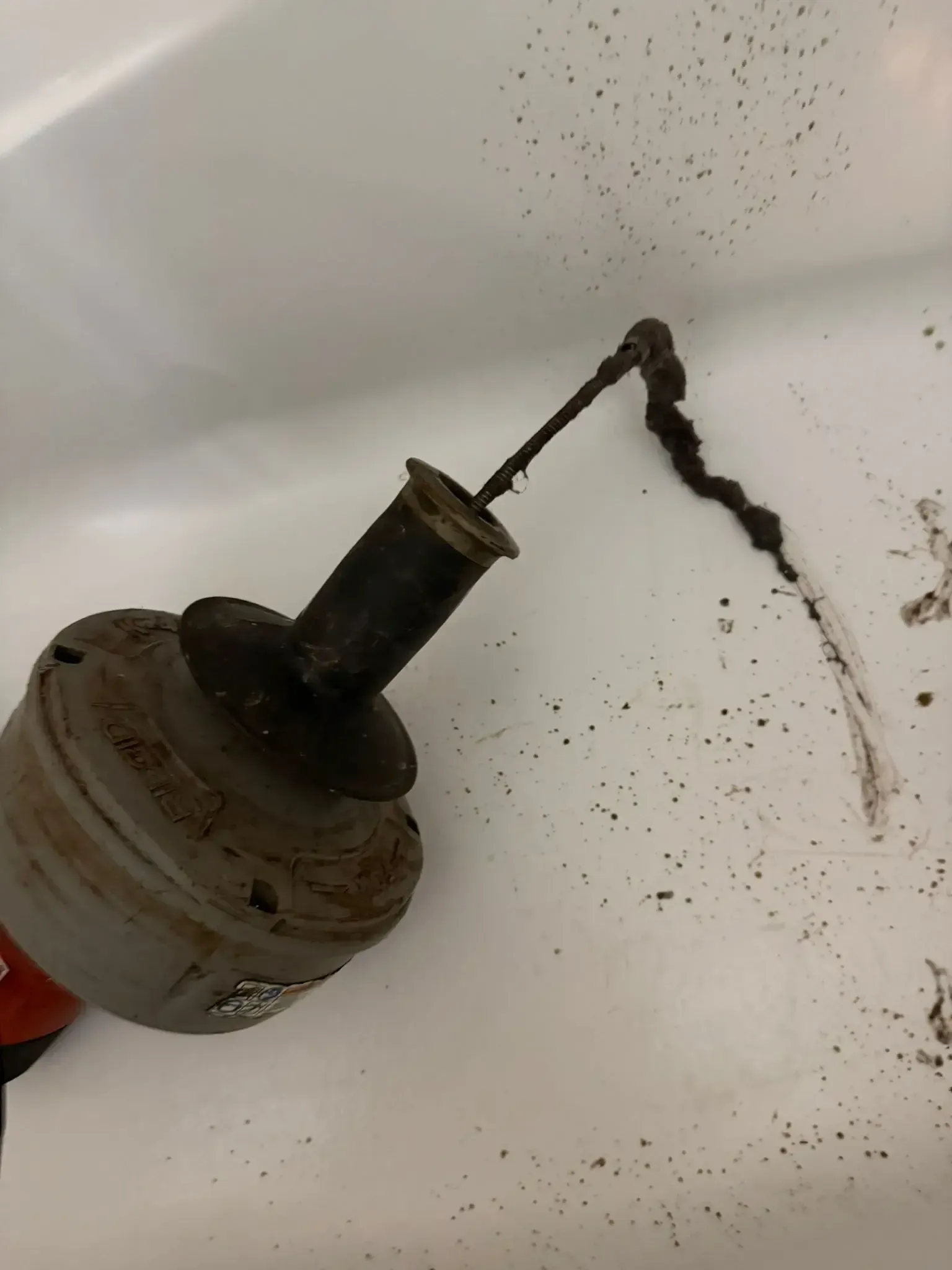 Professional drain cleaning using a plumbing snake to remove hair and debris from a clogged bathtub drain in Oakville