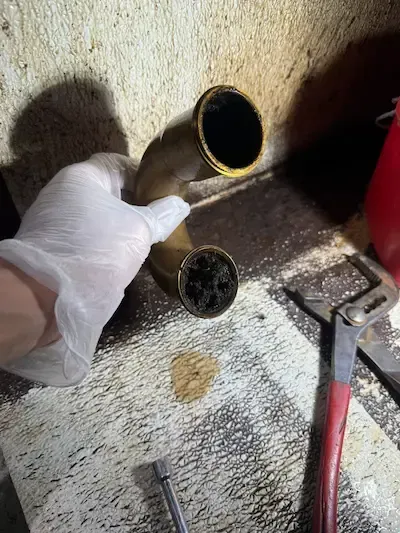 Severely clogged kitchen P-trap filled with hardened grease and sludge causing slow drainage and blockage, requiring professional drain cleaning by emergency plumber Oakville