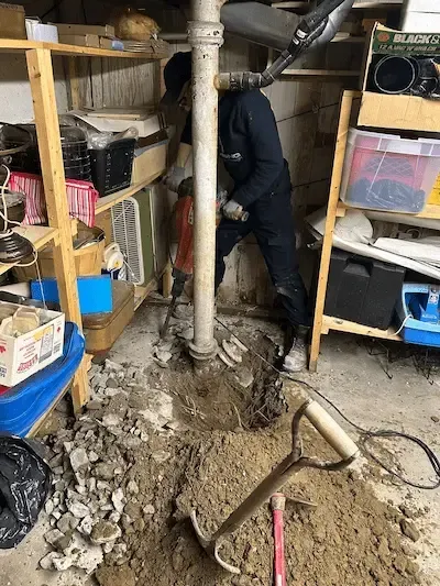 Emergency plumber oakville breaking basement concrete to access and repair broken main drain pipe causing sewage backup and flooding