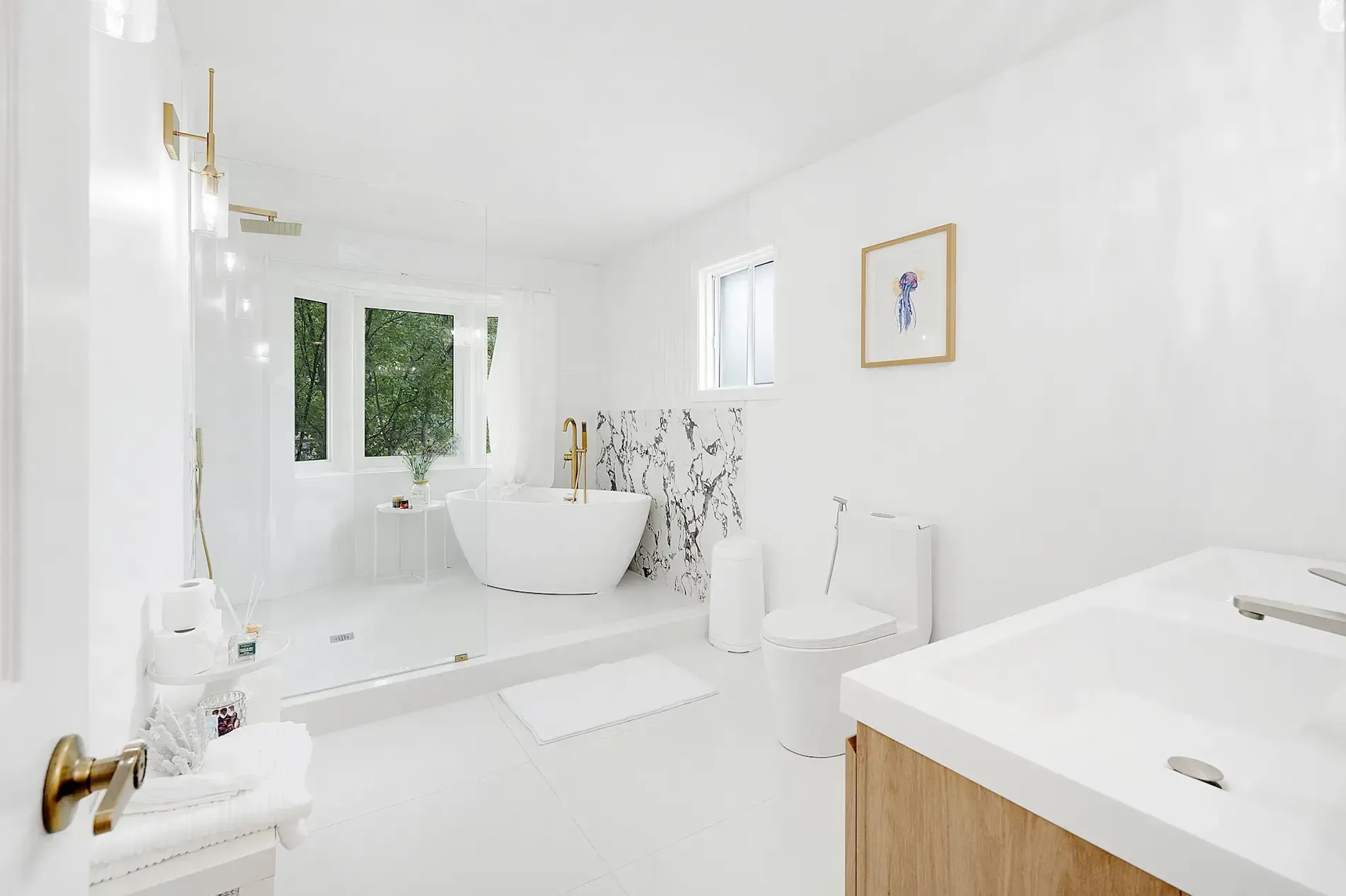 Luxurious white master bathroom renovation with freestanding tub, rain shower, marble accent wall, and dual sink vanity in Oakville.