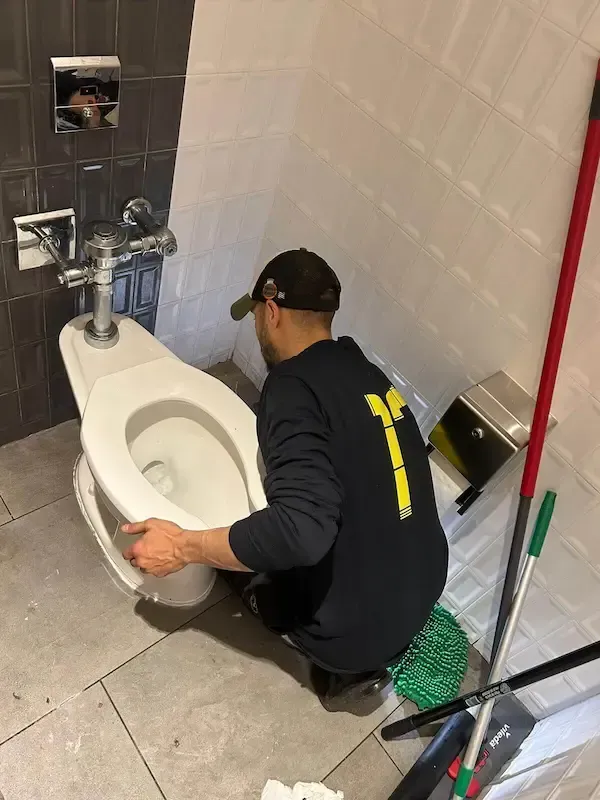 Licensed Oakville plumber repairing and unclogging toilet in bathroom