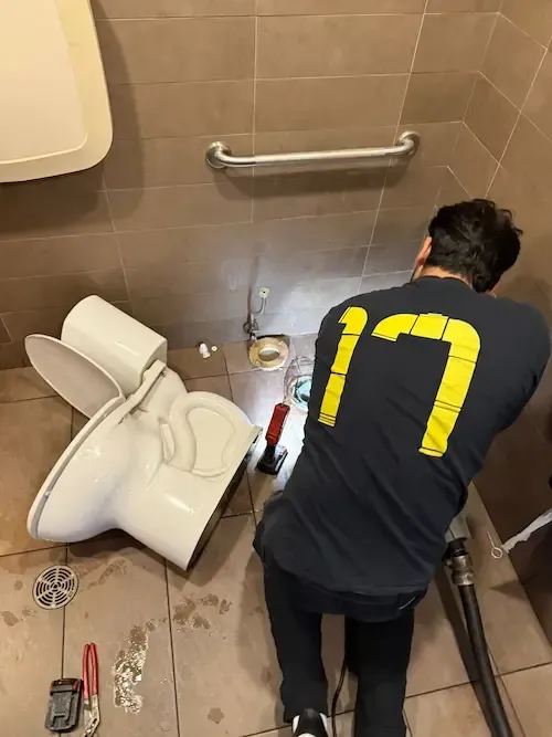Plumber from 17 Plumbing removing a toilet at McDonald’s Oakville to perform snaking on a severely clogged drain.