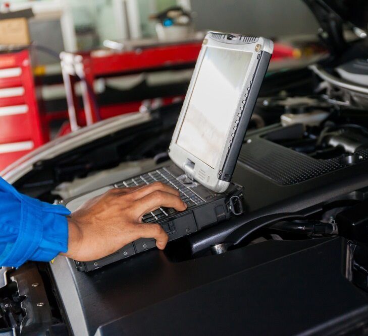 A Person Is Using A Laptop Computer Under The Hood Of A Car — Loch’s Garage In Emerald, QLD