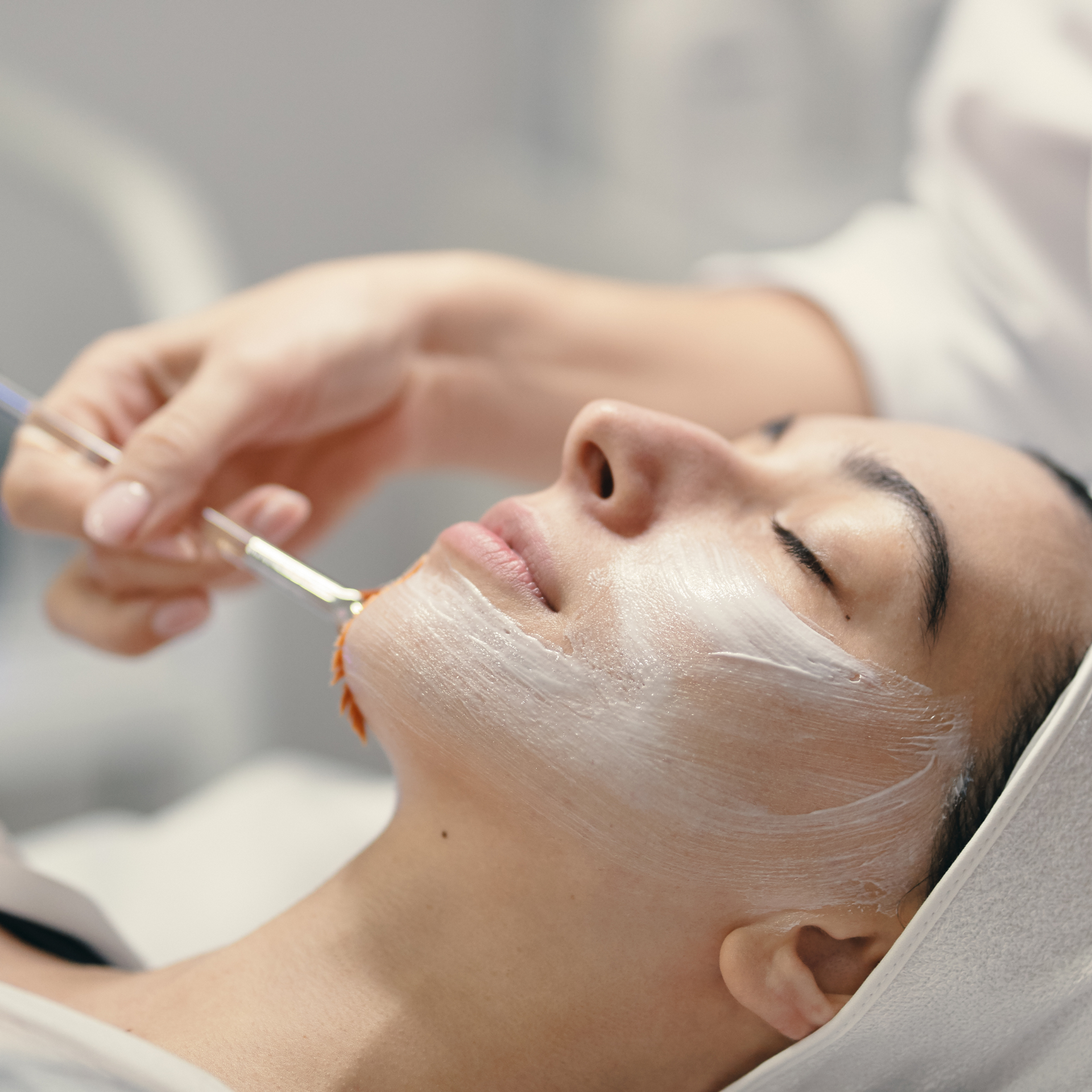 Mani di donna sulle gambe, seduta su una superficie bianca. Sono visibili i piedi nudi.