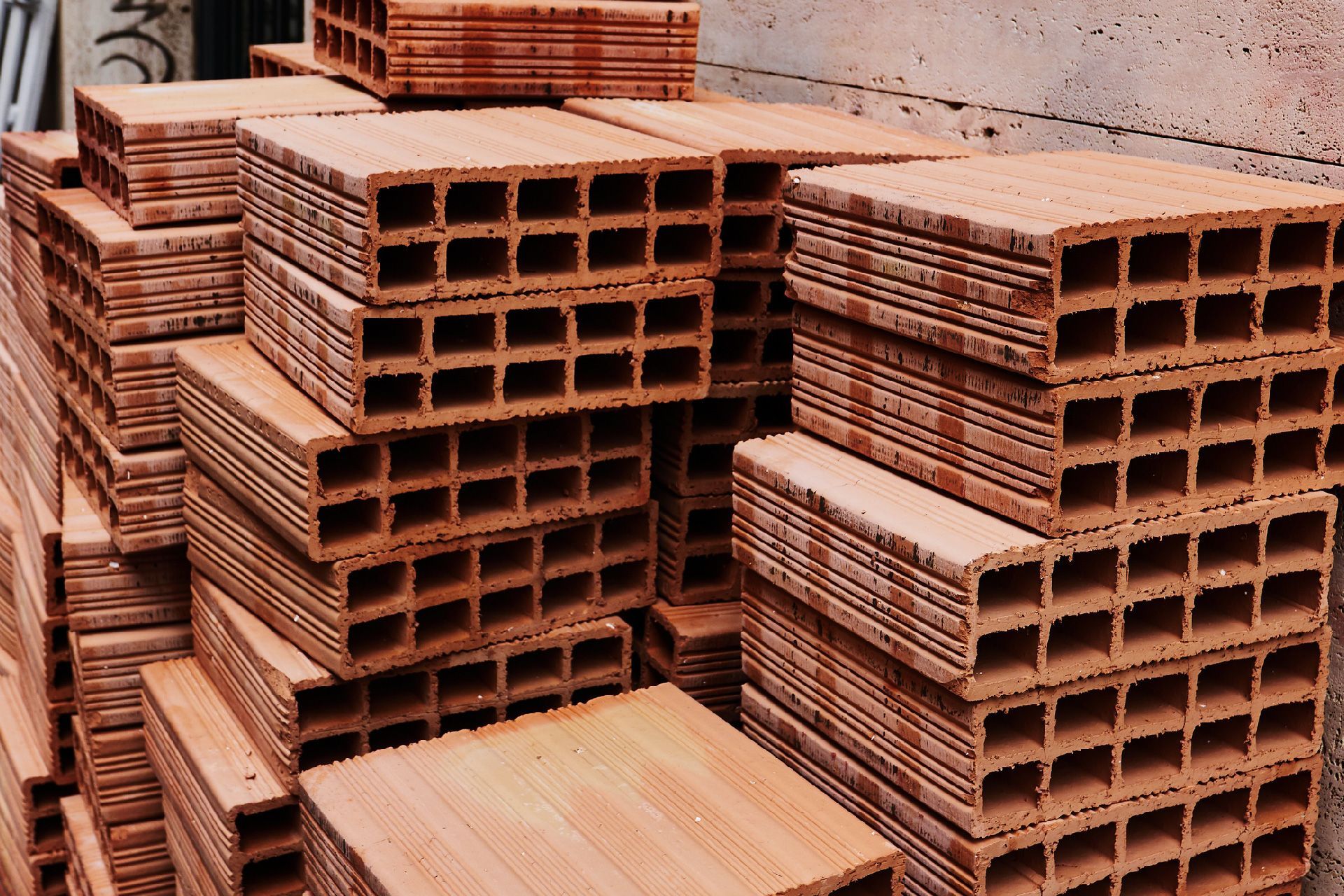 Una gran pila de ladrillos rectangulares y huecos de terracota apilados al aire libre.