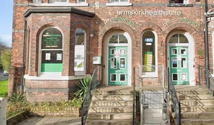 A brick building with green doors and arched windows.