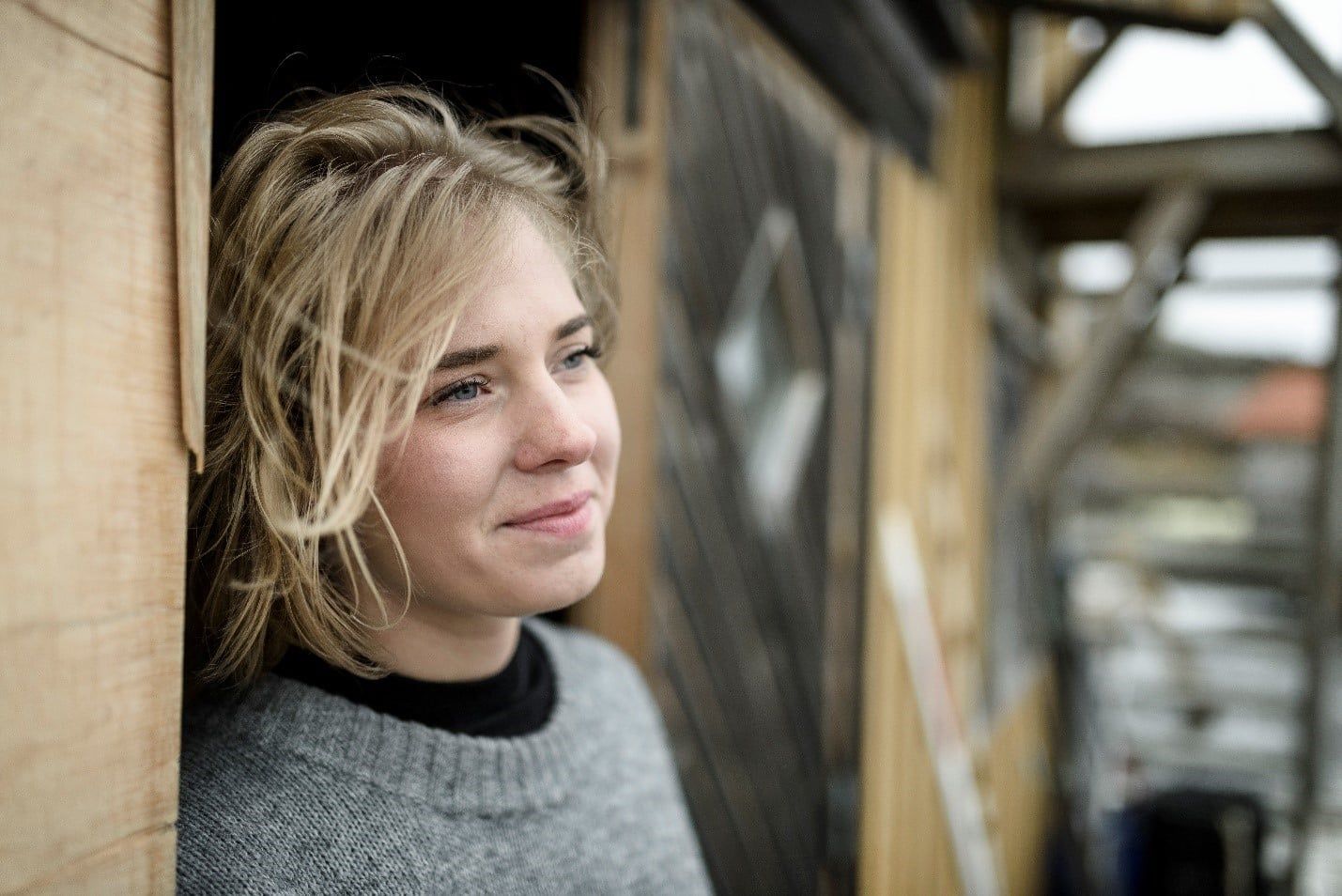 Woman is Leaning Against a Wooden Wall and Smiling — Care FNQ Pty Ltd in Cairns City, QLD