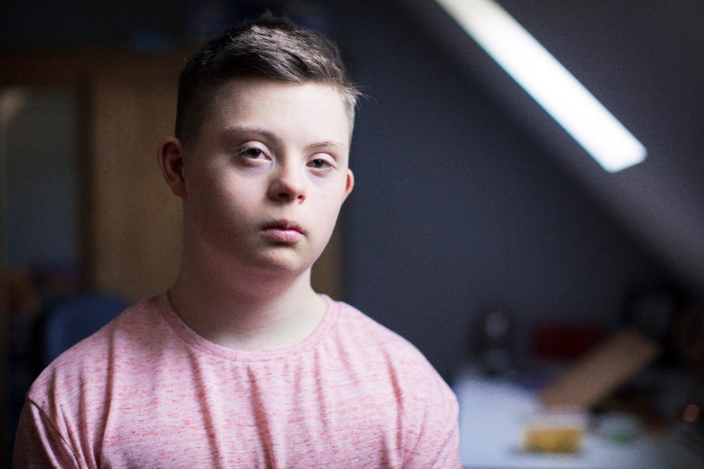 Young Boy With Down Syndrome is Wearing a Pink Shirt and Looking at the Camera — Care FNQ Pty Ltd in Cairns City, QLD