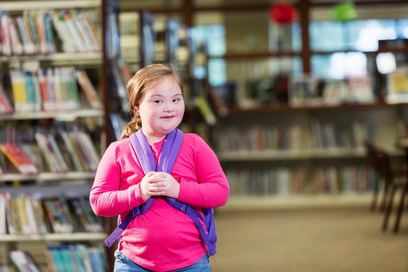 Little Girl is Standing in a Library Wearing a Backpack  — Care FNQ Pty Ltd in Cairns City, QLD