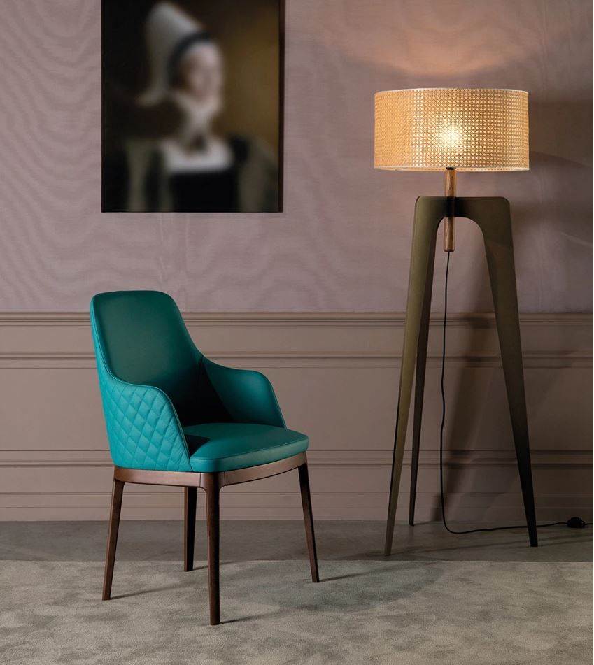 Una sedia e una lampada in una stanza con un dipinto sul muro