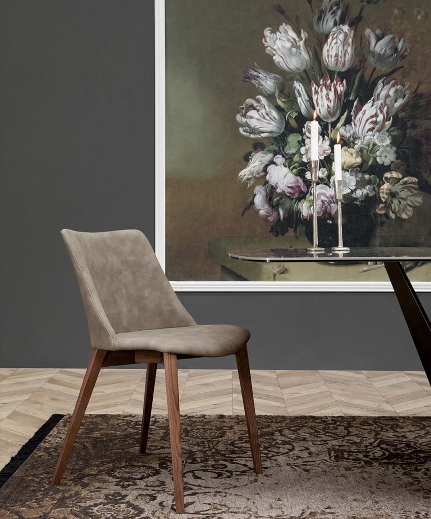 Una sedia è seduta davanti a un dipinto di fiori