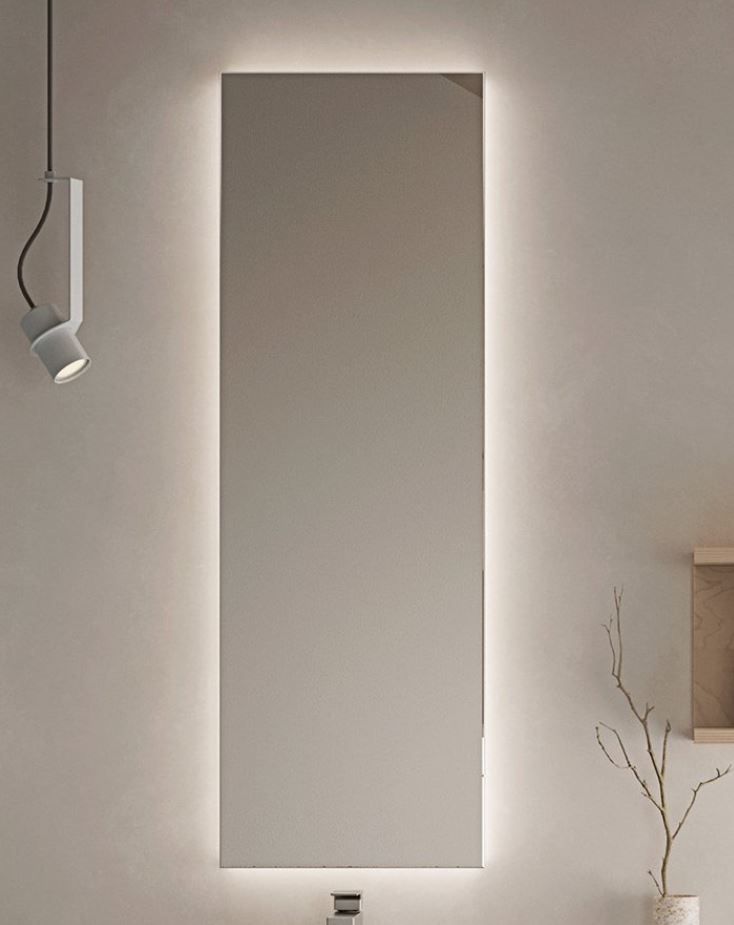 Uno specchio da bagno con una luce dietro è appeso a una parete.