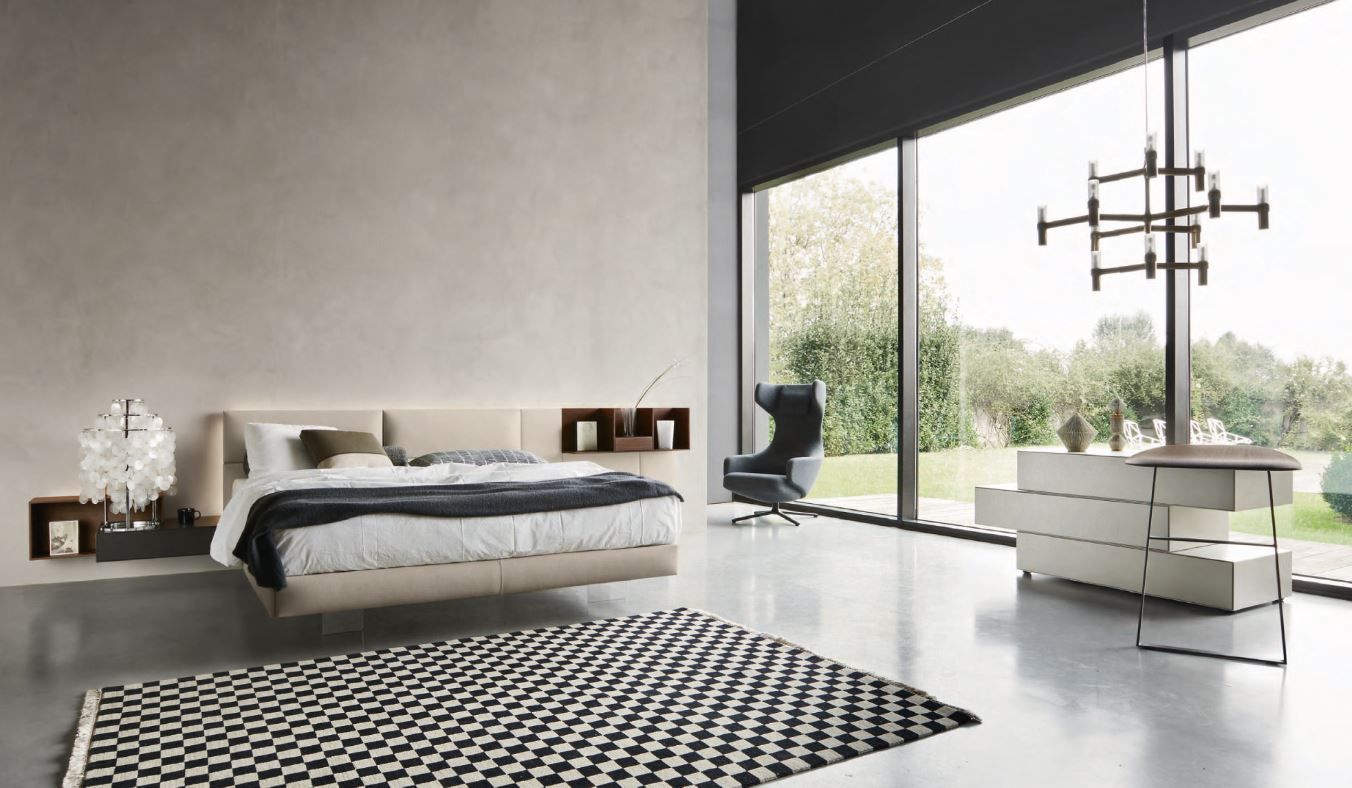 Una camera da letto con un letto, una cassettiera, un tappeto e una grande finestra.