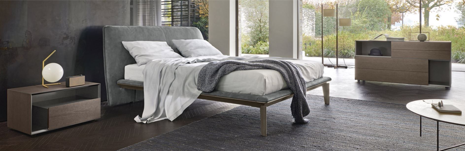 Una camera da letto con un letto, un comodino, una cassettiera e un tavolino.