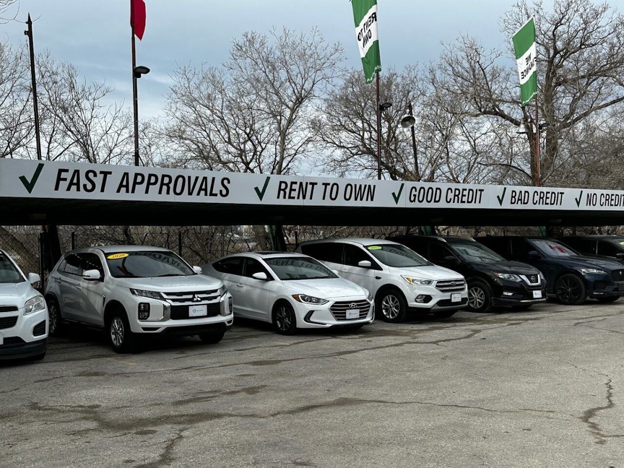 A row of Auto Approved cars are parked under a sign that says 