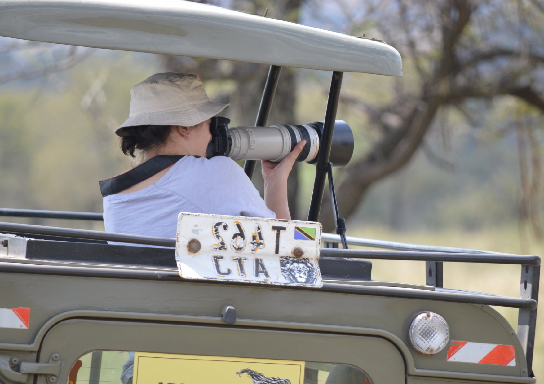 A woman is taking a picture with a camera on the back of a vehicle.