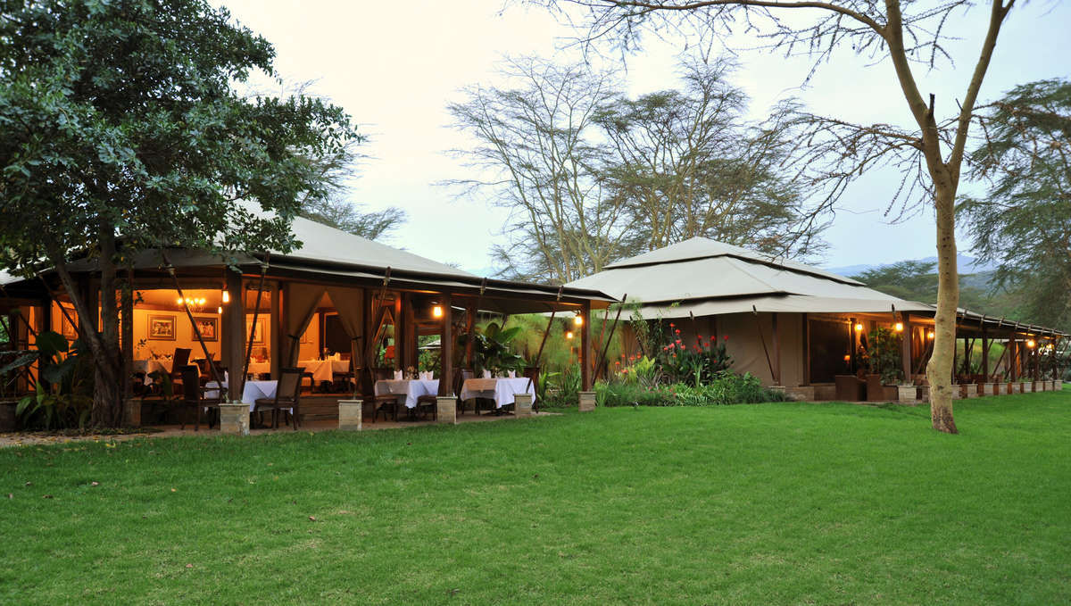 A group of people are sitting at tables outside of a restaurant.