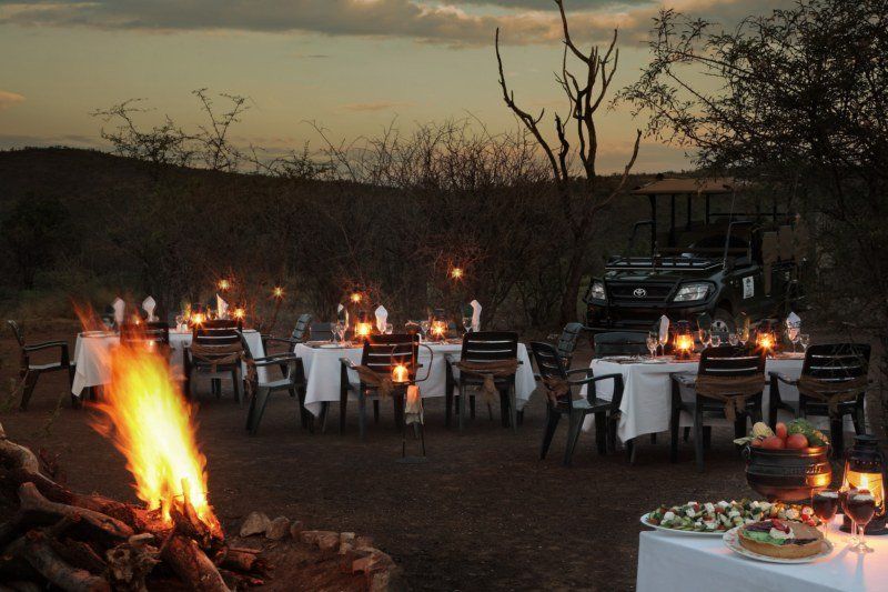 A fire is surrounded by tables and chairs in a field