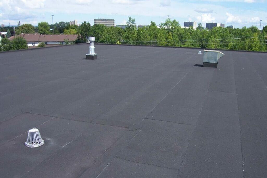 A black roof with a few chimneys on it