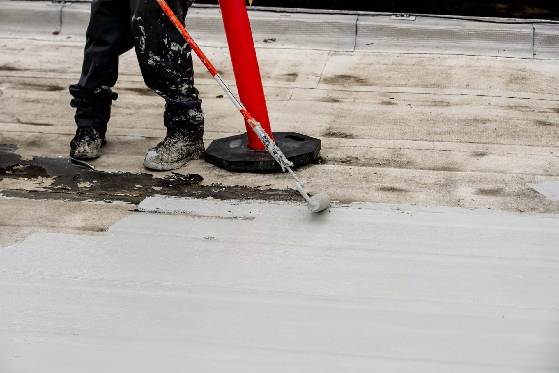 A man is painting a roof with a roller.