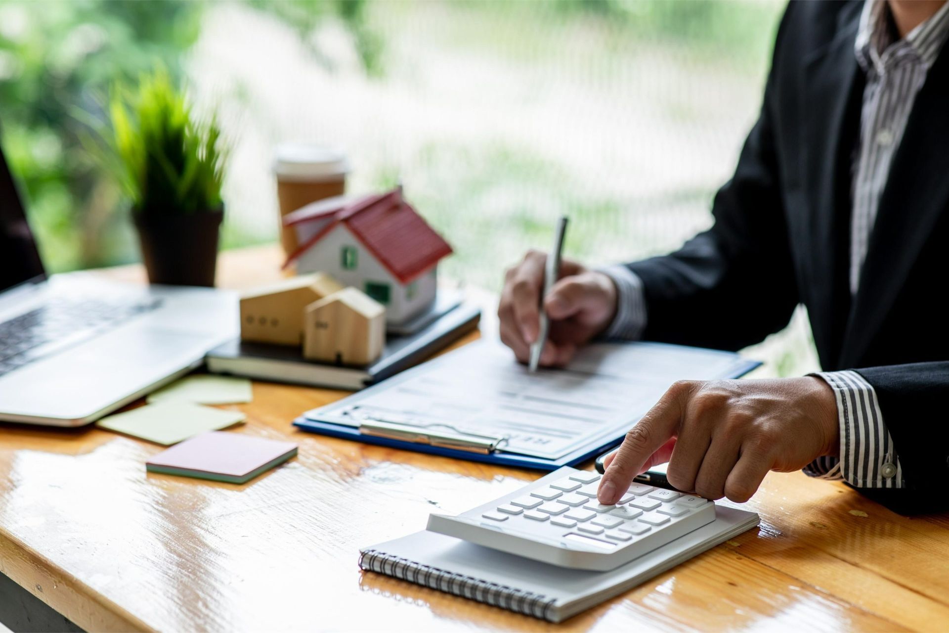 A man is sitting at a table using a calculator and writing on a clipboard.