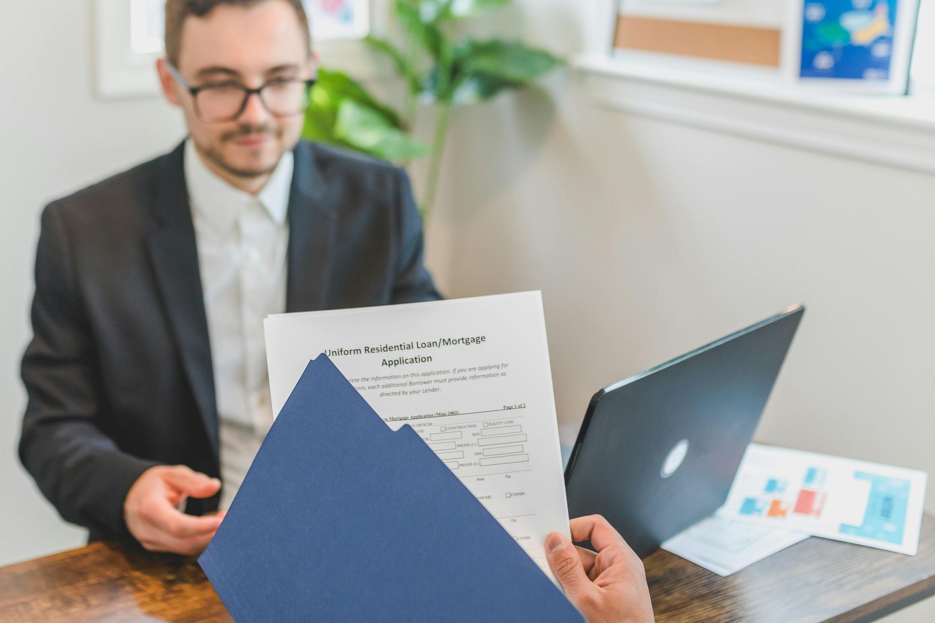 A man is sitting at a table using a calculator and writing on a clipboard.