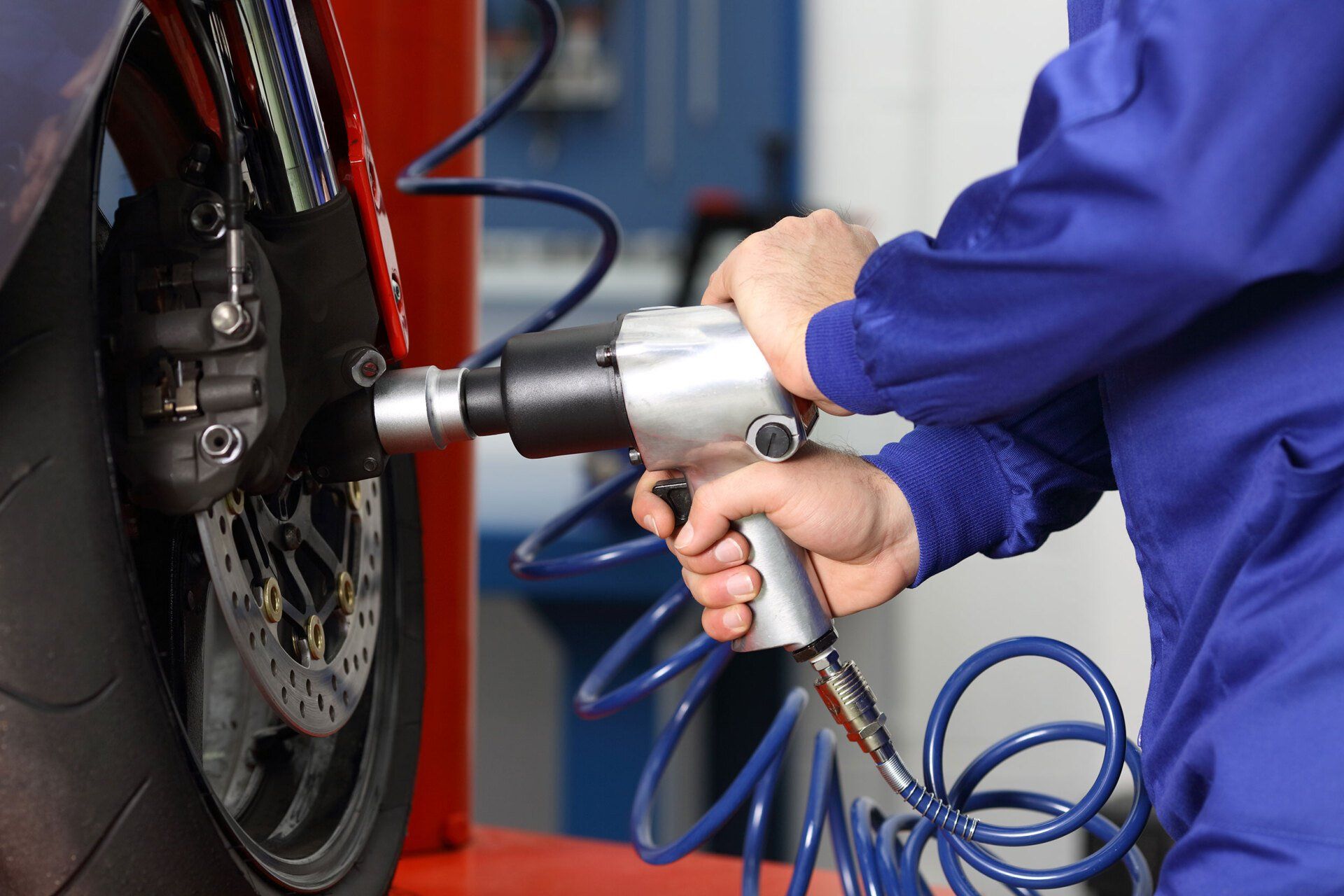 Un uomo sta usando una chiave pneumatica per cambiare una gomma su una moto.