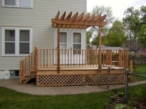 A wooden deck with a pergola and stairs in front of a house.
