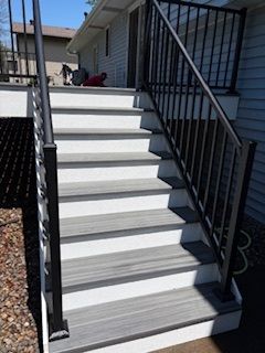 Exterior staircase with gray steps and black railings leading up to a porch.