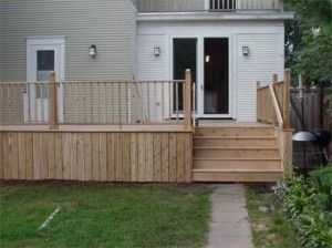 A wooden deck with stairs is in the backyard of a house.