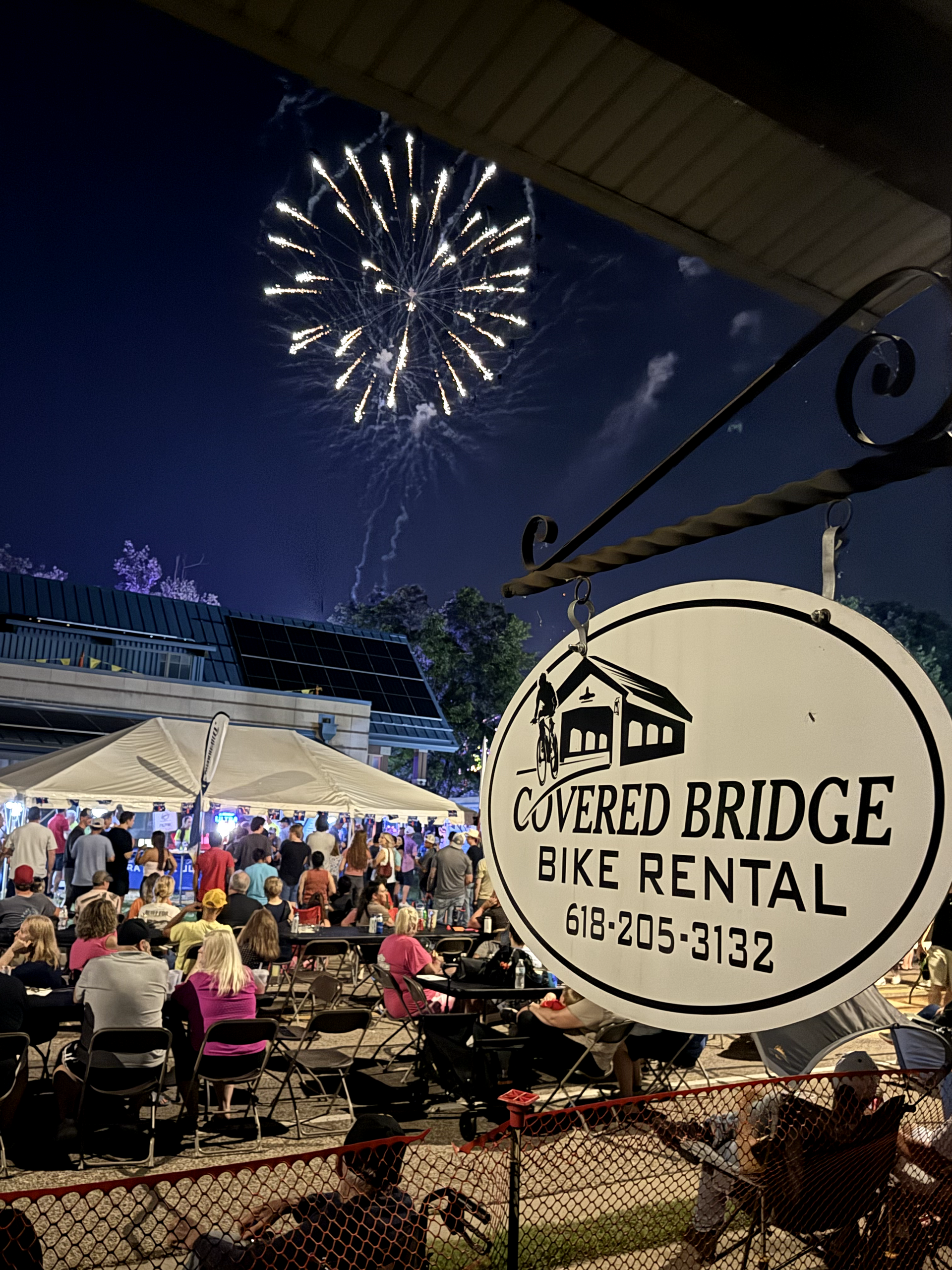 Fireworks over a crowd at an outdoor event with a 